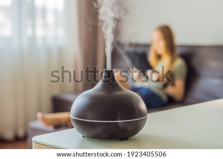Aromatherapy Concept. Wooden Electric Ultrasonic Essential Oil Aroma Diffuser and Humidifier. Ultrasonic aroma diffuser for home. Woman resting at home Royalty-Free Stock Photo #1923405506