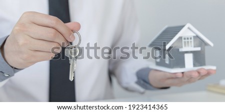 Sales manager or real estate agent prepares to hand over the keys and the house together with the insurance to the customer, Attention to property services and insurance concept.