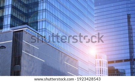 Downtown corporate business district architecture. Glass reflective office buildings against blue sky and sun light. Economy, finances, business activity concept. Rising sun on the horizon.