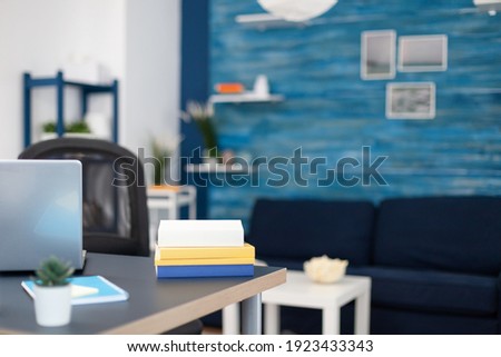 Stack of books on modern furniture in empty office. Cozy home living room with nobody in it with beautiful interior design.