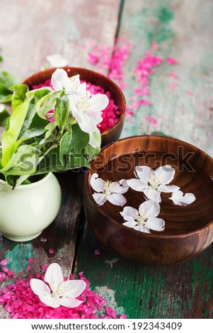 Spa setting on old wooden background. Water with aroma oil, sea salt, flowers. Selective focus, vertical.