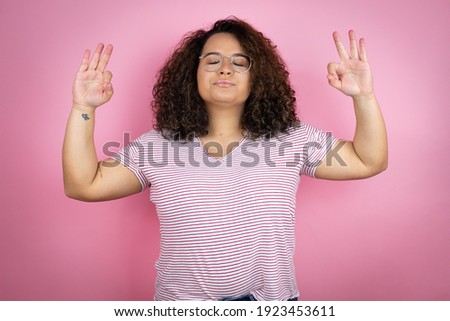 Young african american woman wearing red stripes t-shirt over pink background relax and smiling with eyes closed doing meditation gesture with fingers
