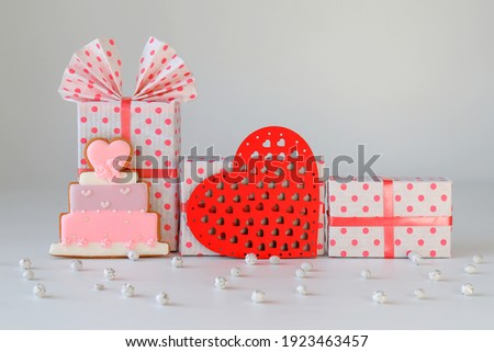 Beautiful pink boxes for gifts with a ribbon, a red wooden heart and a gingerbread cake on a gray background.  Red box,  Holiday concept, Mothers day, wedding, birthday