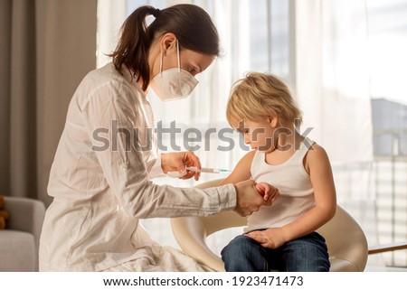 Little toddler child, blond boy, getting injection in consulting room from pediatrician, annual vaccination.