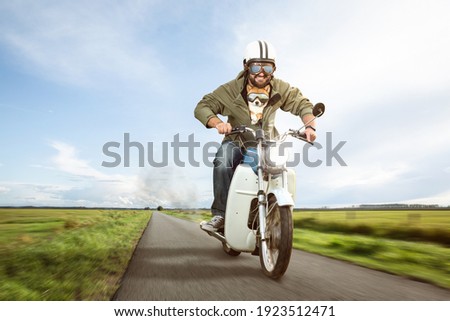 Funny biker riding a moped with his dog Royalty-Free Stock Photo #1923512471