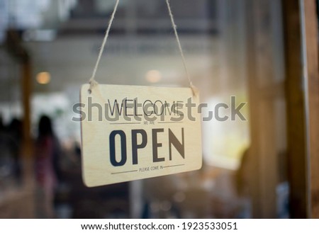 A wooden sign hanging in front of a mirror at the entrance of the coffee shop Concept of opening shop in the morning
