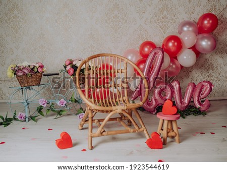 San Valentin mini photoshoot for babies and toddlers in a photo studio with a chair, flowers and balloons
