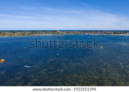 People swim in the sea on a kiteboard or kitesurfing. Summer sport learning how to kitesurf. Kite surfing on Puck bay in Jastarnia, Poland, Europe aerial drone photo view
