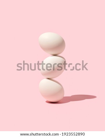 Easter white eggs stacked  on top of each other against pink background. Creative holiday layout. Minimal raw food concept.