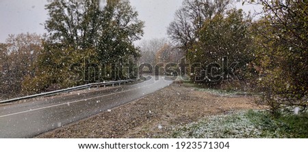 Wet autumn road in the forest, the first snow fell. Royalty-Free Stock Photo #1923571304