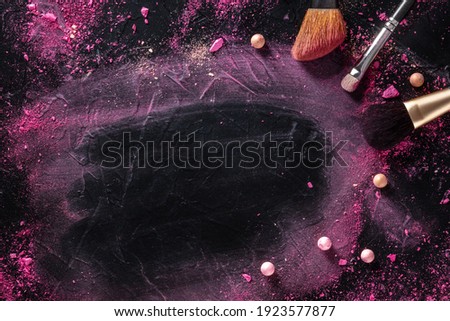 Make up brushes and pearls, shot from above on a black background with copy space
