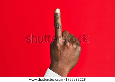 Arm and hand of african american black young man over red isolated background counting number one using index finger, showing idea and understanding 