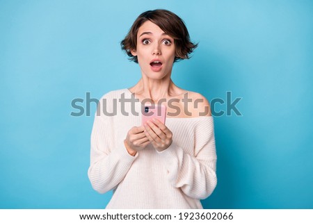 Photo of young beautiful shocked surprised amazed girl see bad comment use phone isolated on blue color background