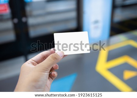 hand holding blank card in subway station, card mockup template