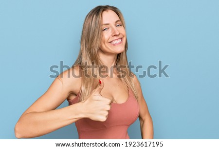 Beautiful caucasian woman wearing casual clothes doing happy thumbs up gesture with hand. approving expression looking at the camera showing success. 