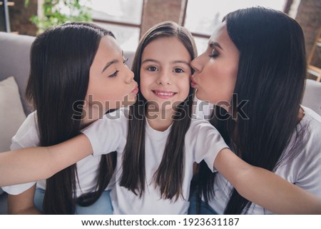 Self-portrait of beautiful cheerful careful girls friends having fun kissing sitting on divan at house flat apartment indoors