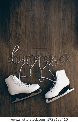 Women skates pair of boots  with a hearts of laces on a dark wooden surface. With space for text on top. Concept of love.