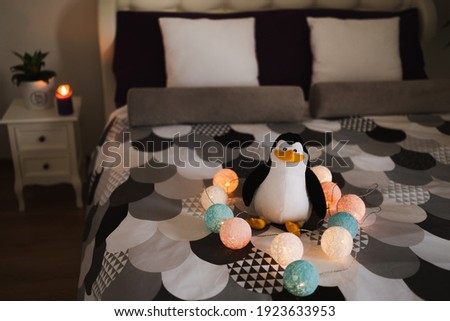 Toy plush penguin on a bed in the bedroom