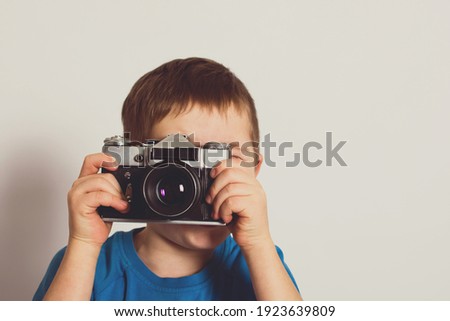 Small child taking photo with retro film camera. Old technology concept with copy space.