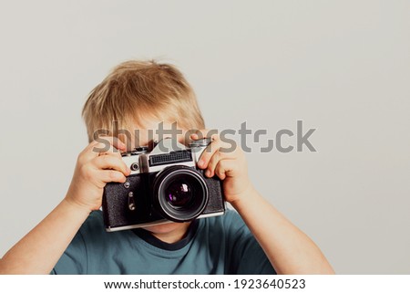 Little boy taking photo with old film camera. Retro technology concept with copy space.