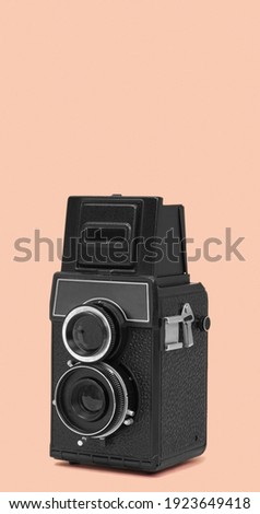 a black retro medium format film camera on a pale pink background, with some blank space on top, in a vertical format to use for mobile stories or as smartphone wallpaper