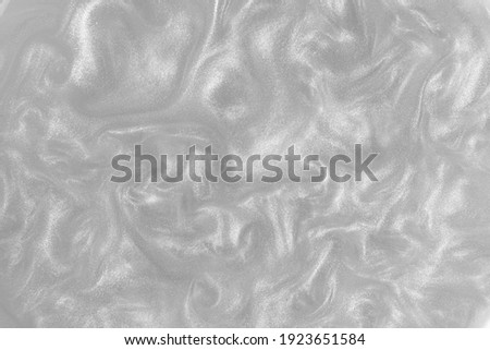 Silver paint background. Motion of the shiny liquid. Color of the year 2021 Ultimate Grey. Waves on a glittering liquid surface. Abstract gray background.