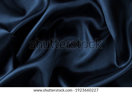 Dark blue silk satin wavy soft folds texture background.