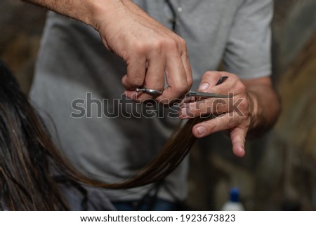 closeup hairdresser hand with scissors on workplace. Hairdresser taking woman hair for cut. Shallow depth of field