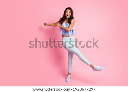 Full size photo of optimistic brunette lady dance wear blue top trousers sneakers isolated on pink color background