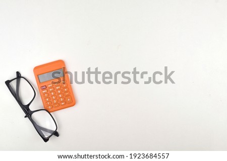 Selective focus image of calculator and spectacles on a white background with copy space.