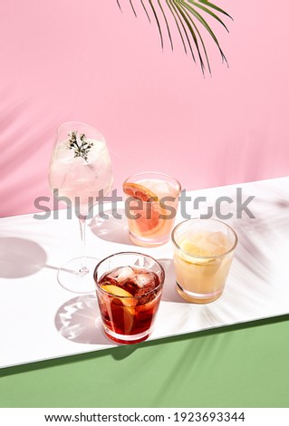 Summer cocktail with fruit and ice. Drink on white table over pink wall in sunlight with palm leaf shadow. Summer, tropical, fresh cocktail concept. Royalty-Free Stock Photo #1923693344
