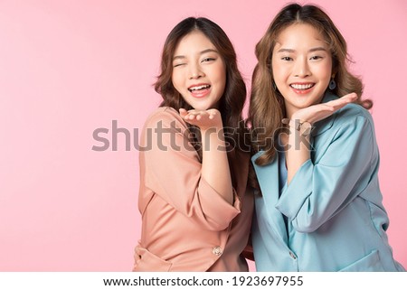 Two young woman enjoying together portrait isolated on pink background