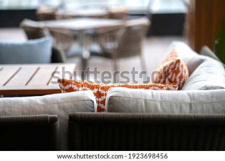 close up colorful soft pillows cushion arrange on nature material dining chair with blur patio area background interior design concept