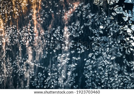 Ice blocks floating in dark waters covered in fog. Abstract landscape in sunny morning light. Picturesque shapes and forms.
