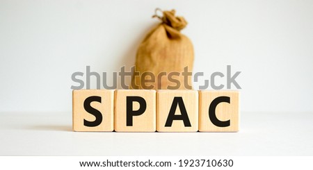 SPAC, special purpose acquisition company symbol. Wooden cubes with word 'SPAC' on beautiful white background, copy space. Canvas bag. Business and SPAC, special purpose acquisition company concept.