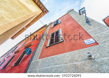 Chiusi, Italy street looking up view in small historic medieval town village in Umbria with red yellow bright vibrant colorful painted wall