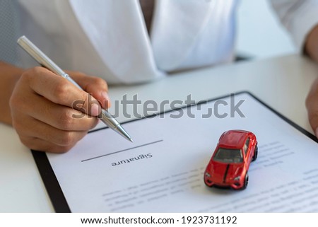 The insurance agent is letting the insured sign the contract. After the concept of car insurance. And contract insurance concept agreement Making rental and purchase agreements for cars