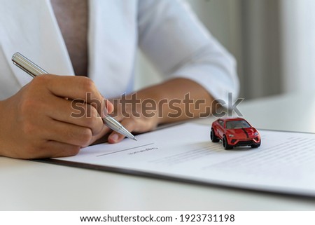 The insurance agent is letting the insured sign the contract. After the concept of car insurance. And contract insurance concept agreement Making rental and purchase agreements for cars