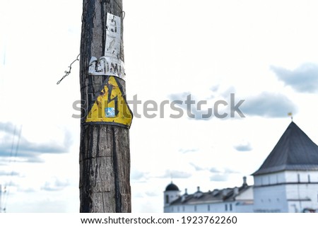 Sign caution electricity. Current. A sign on a wooden pole.