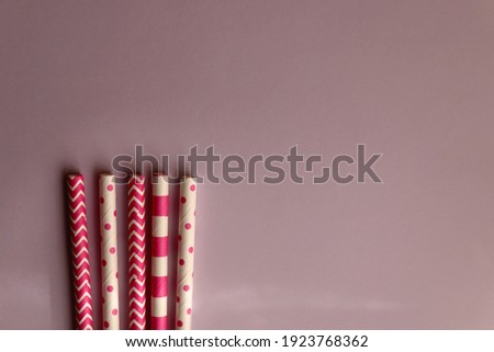 Pink and white paper straws on pastel pink background. Top view.