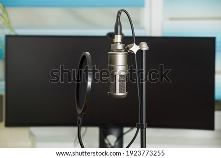 The professional condenser microphone attached to the rack stands next to the desktop