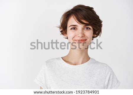 Head shot of beautiful caucasian woman with short haircut, smiling and looking confident, standing in t-shirt on white background. Royalty-Free Stock Photo #1923784901