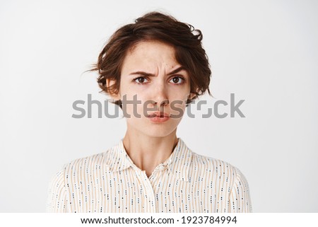 Portrait of confused young woman stare skeptical at camera, raise eyebrow in disbelief, looking at you, standing on white background. Royalty-Free Stock Photo #1923784994