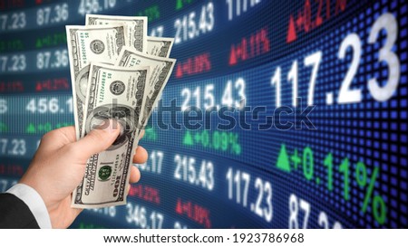 American dollar in man's hand and stock market screen, money chart background Royalty-Free Stock Photo #1923786968