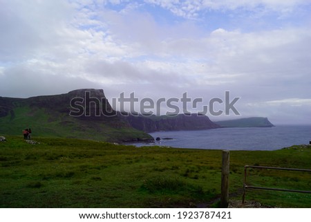 In this picture we see the coastline in Neist point. The coastline consists of rocks that are completely covered with fresh green grass. In the background we can clearly see the ocean.