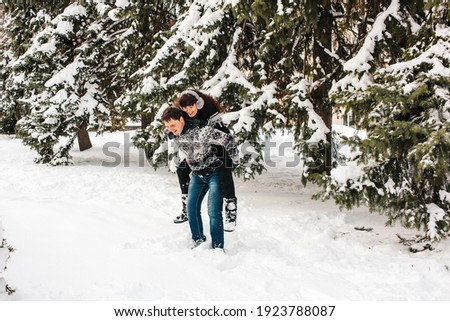 Winter couple have fun playing in the snow outdoors. Young joyful happy people. Winter fun