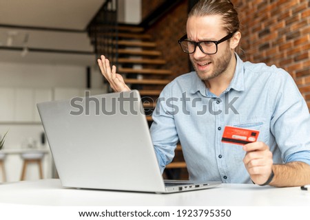 Young businessman faced with a problem while paying by credit card, not enough money in the bank account, card blocked, computer shows an error, does not load the page, shocked by the amount of money Royalty-Free Stock Photo #1923795350