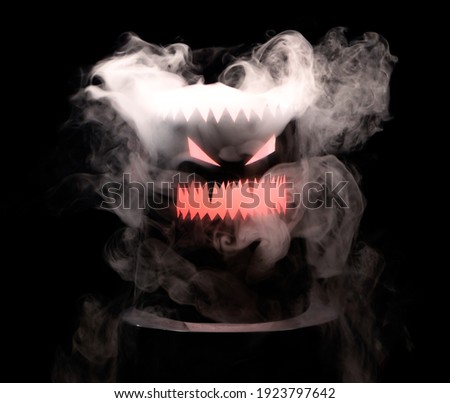 Evil grin head shrouded in white smoke clubs on a black background