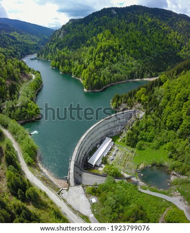 Aerial drone view above Petrimanu hydroelectric Lake and its arched dam. Springtime in Latorita Massif, all the beech trees are bright green. Carpathia, Romania. Royalty-Free Stock Photo #1923799076