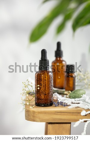Bottles of dark amber glass with essential oil, massage jade roller and tropical leaves Royalty-Free Stock Photo #1923799517
